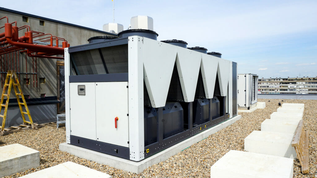 Weißer luftgekuehlter Kaltwassersatz mit Schallschutz auf Dach eines Industriegebaeudes